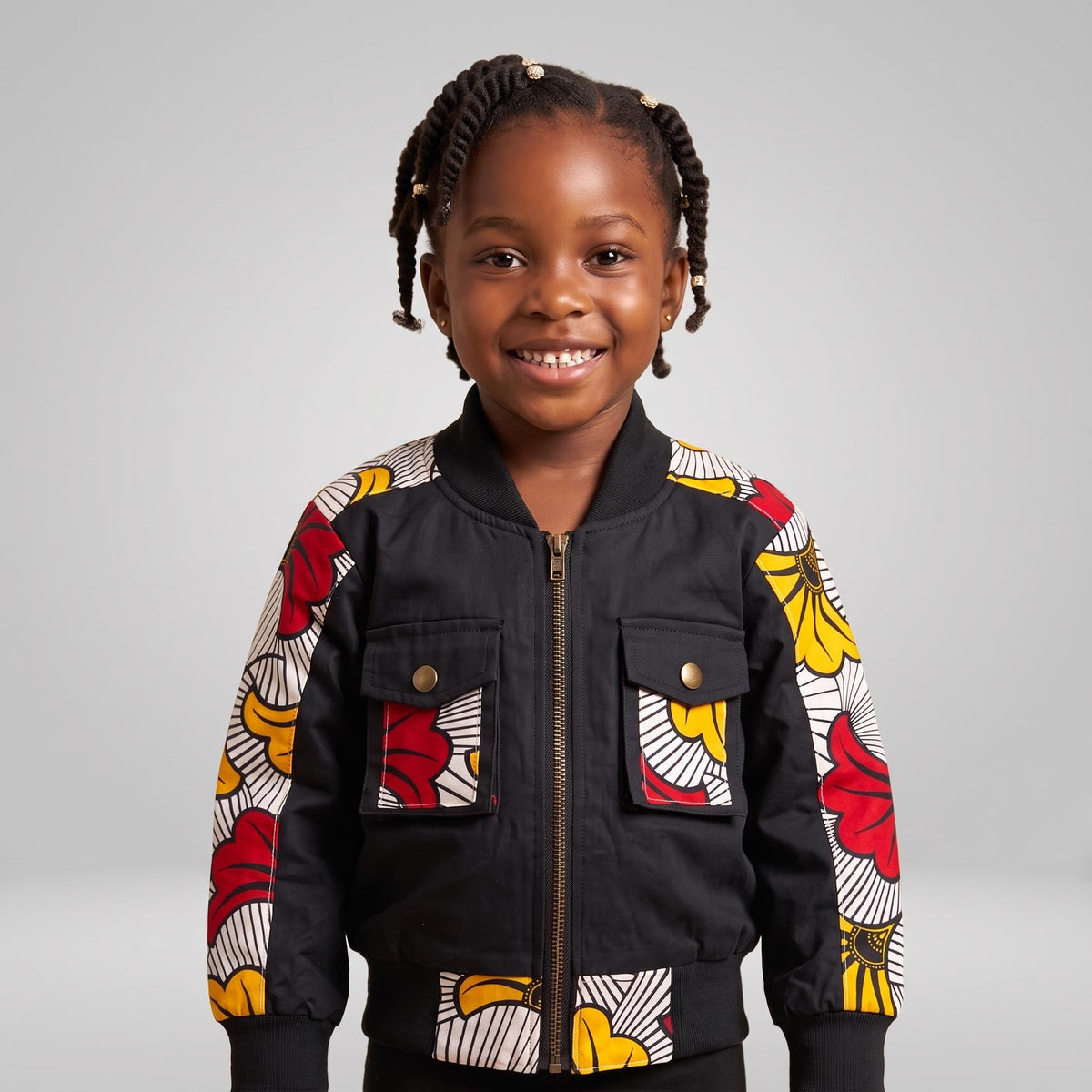 Bomber aviateur noir pour fille MPESA Urbain, avec détails en wax fleuri sur les manches, les poches et le bas de la veste.