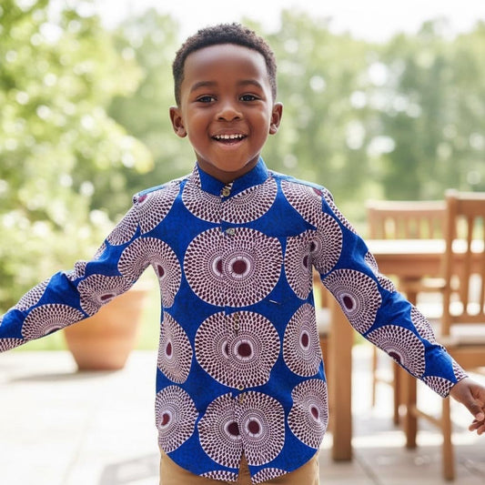 Enfant portant une chemise longue en wax deux-en-une avec manches amovibles grâce à un bouton, permettant de passer facilement de manches longues à manches courtes.