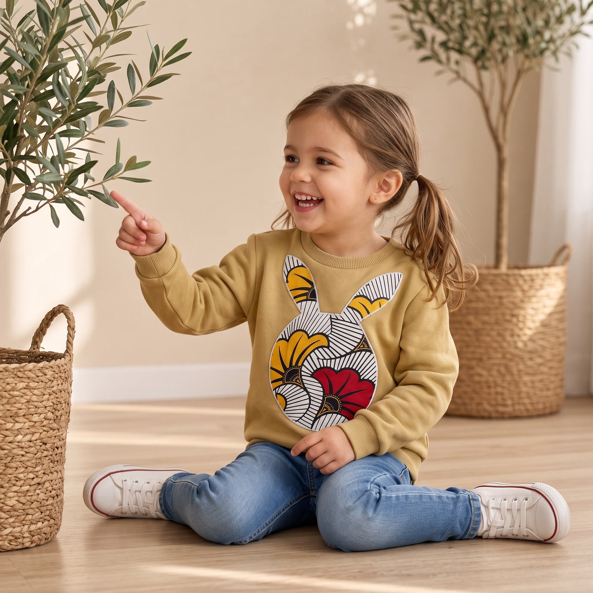Gros plan sur la tête de lapin en wax « Fleur de mariage » qui décore le sweat-shirt moutarde pour enfant MPESA.