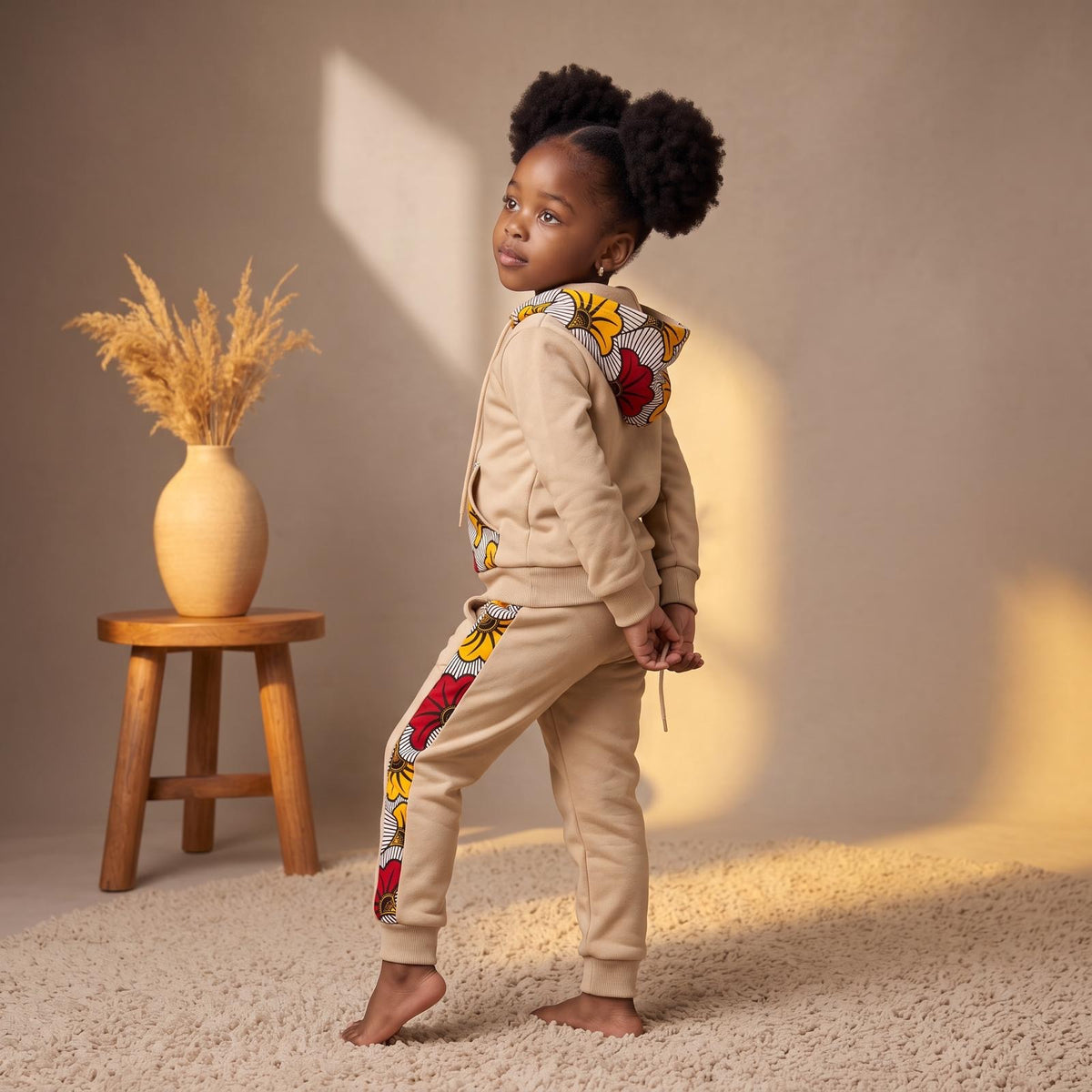 Ensemble jogging enfant mixte MPESA beige, avec motifs wax jaunes, rouges, noirs et blancs sur la capuche, les poches de la veste et les côtés du pantalon.